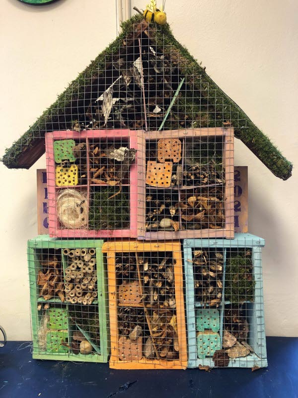 Flervåningshus i form av olika färgglada boxar staplade på varandra med olika skrymsel för bi och insekter. Foto.