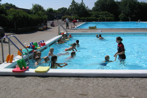 Ett flertal barn i en stor bassäng. Foto.