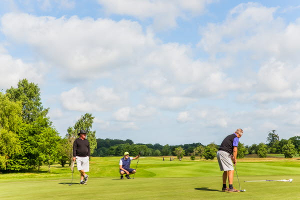 Tre personer spelar golf. Foto.