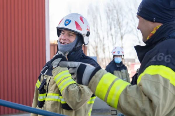 Två brandmän i arbetskläder och hjälm. Foto. 
