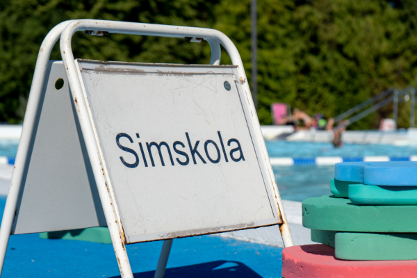 Skylt vid en bassäng med texten Simskola. Foto.
