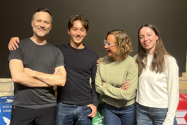 Fyra personer (en familj) håller om varandra och skrattar. Foto.