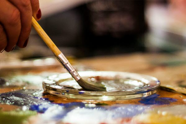 En hand som håller i en pensel som målarFoto.